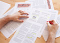 A person has a stack of papers on their desk, to review