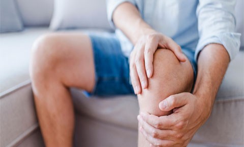 A close up view of a person holding their knee, as though the knee hurts
