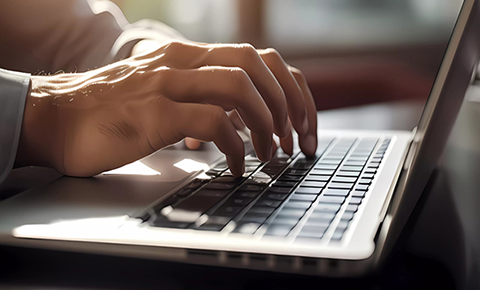 Hands typing on a laptop keyboard