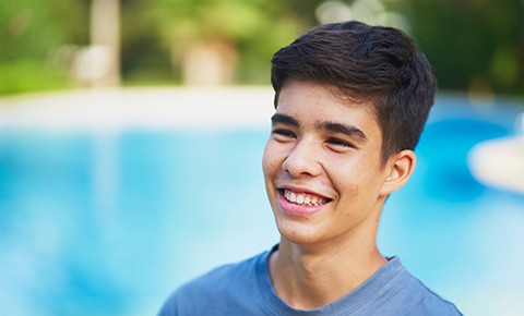 Portrait of a cheerful teenager laughing against swimming pool