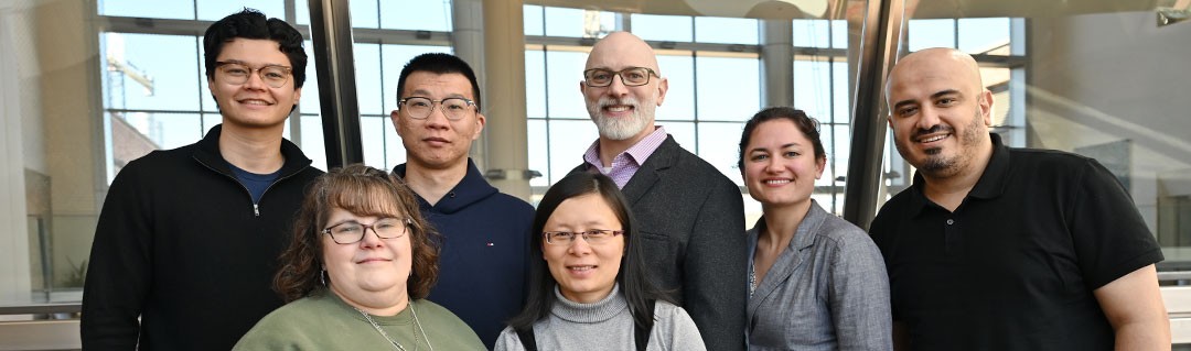 Group of people standing against a patterned background.