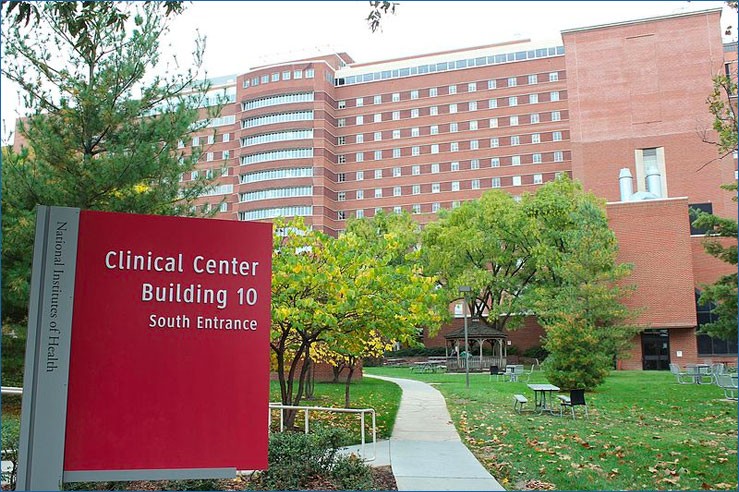 The South Building of the NIH Clinical Center, shown with a large sign on the pathway in the foreground.