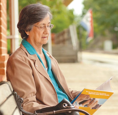 Elderly woman reading a book sitting outside