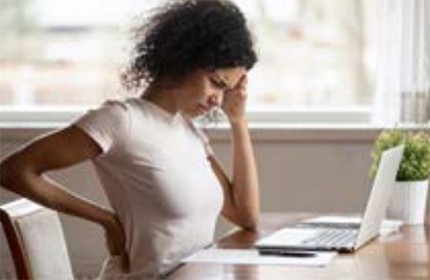 Distressed woman holds her head and her back because her back hurts