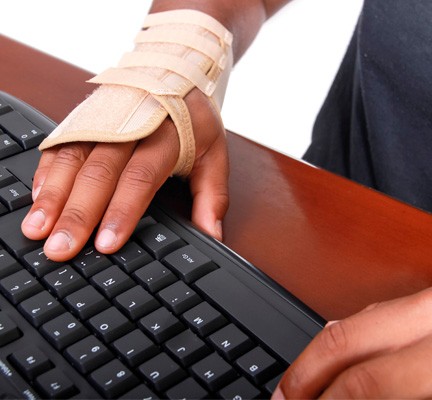 Photo of a hand in a brace typing on a keyboard