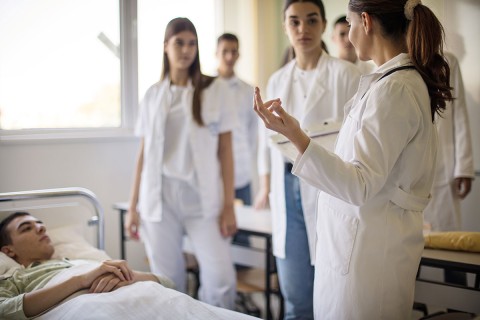 Group of medical students and their mentor gathered around a patient.