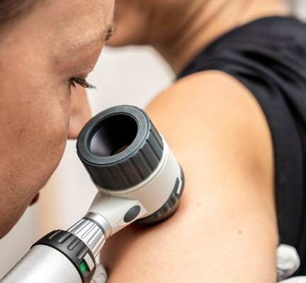 Photo of a doctor closely examining the skin on a patient's arm.