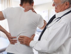 Man grabbing back and doctor examining back