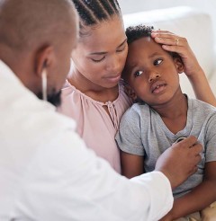 Male doctor checking on child patient being held by a parent