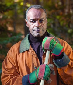 A man wearing work gloves and holding a tool