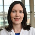 Headshot of a female medical professional with long, dark hair.