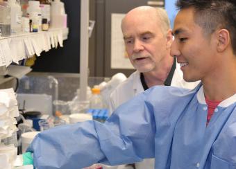 Dr. O’Shea (left) watches as NIAMS visiting fellow Kigoshi Hirahara M.D. Ph.D. works in the lab of the NIAMS Molecular Immunology and Inflammation Branch.