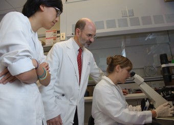 Robert A. Colbert M.D. Ph.D. Amy Petrik Ph.D. and Grace Kwon Ph.D. Examine Skin Fibroblasts under a Microscope.