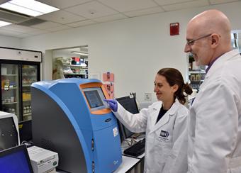 2 scientists demonstration a machine 