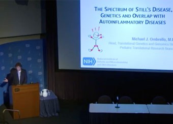 Photo of Dr. Ombrello presenting in front of a large screen.
