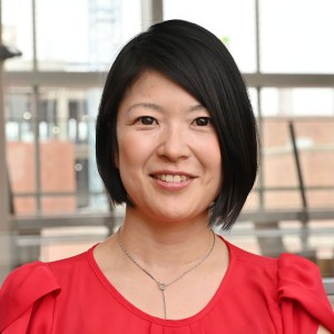 Headshot of an asian woman with short hair, in professional attire.