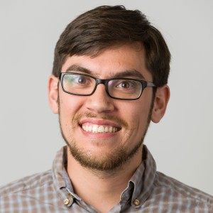 Headshot of a young man with short hair and glasses.