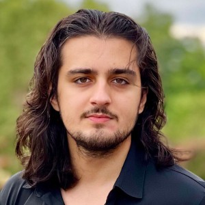 Headshot of a young man with long, dark hair.