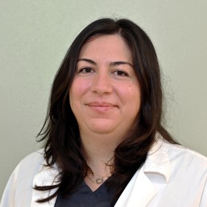 Headshot of a woman with long dark hair wearing a lab coat.