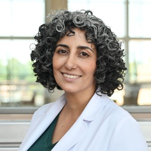 Headshot of a woman with curly hair wearing a labcoat.