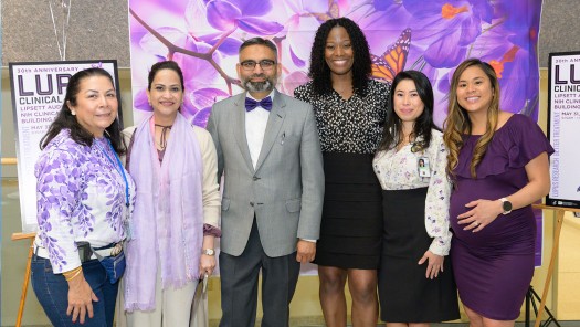 Group of lively people in front of a brightly colored banner.