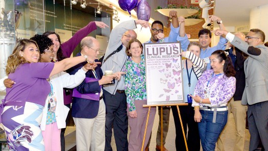 Group photo of people all pointing to a Lupus poster.