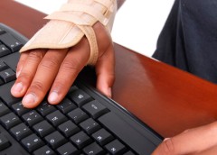 Photo of a hand in a brace typing on a keyboard