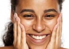 Photo of smiling woman holding her hands to her cheeks